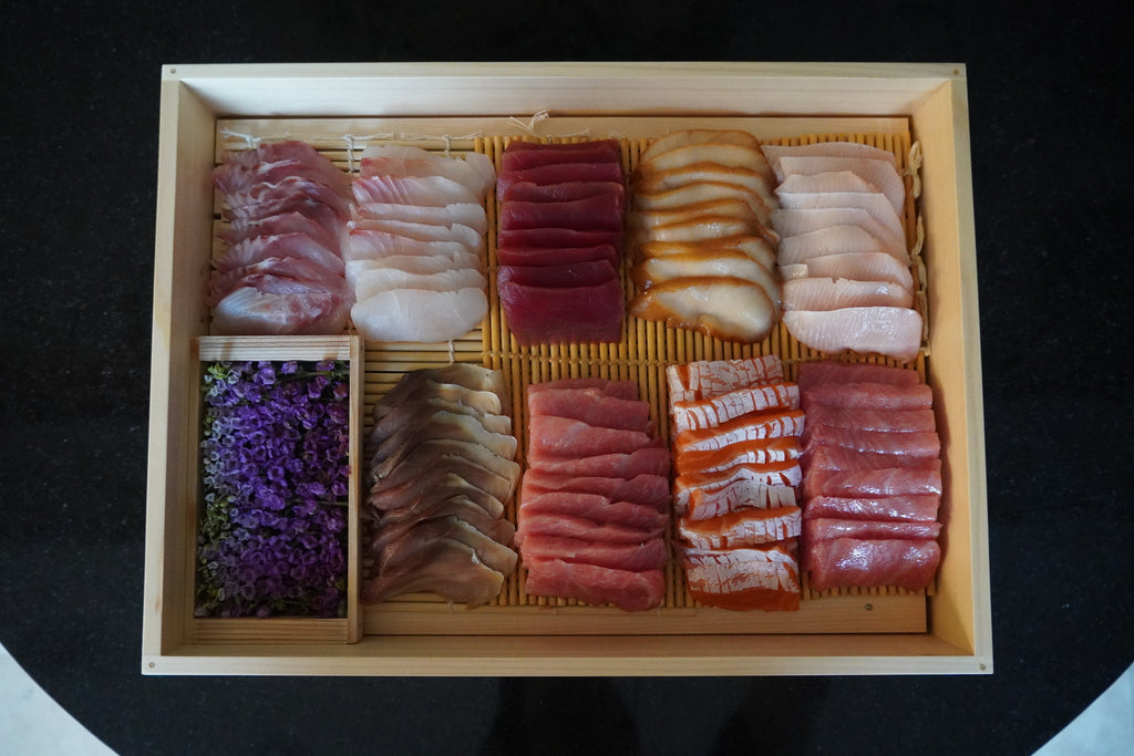 Assorted sushi in a wooden box on a dark surface 