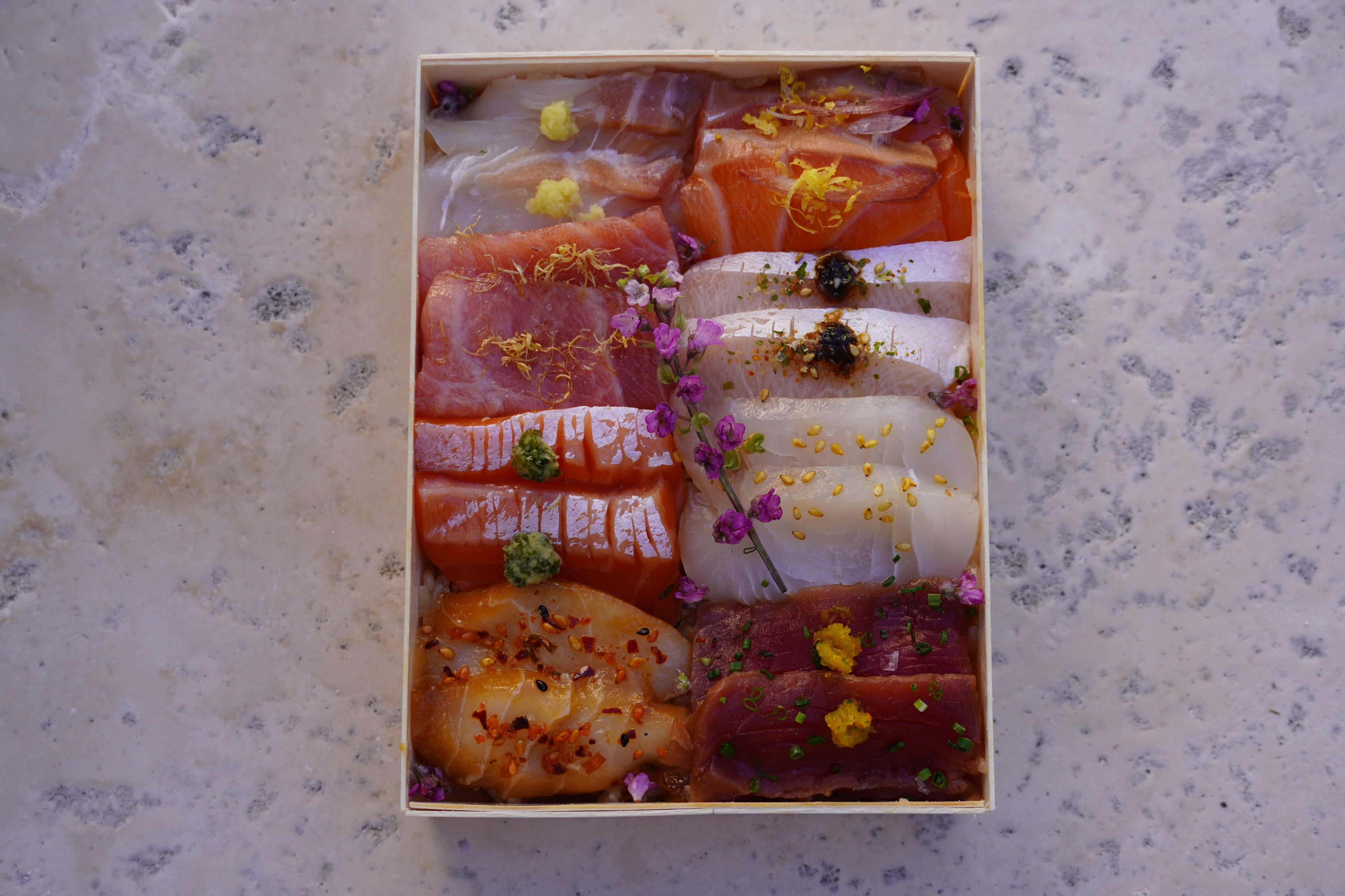 Assorted sushi in a wooden box on a textured surface