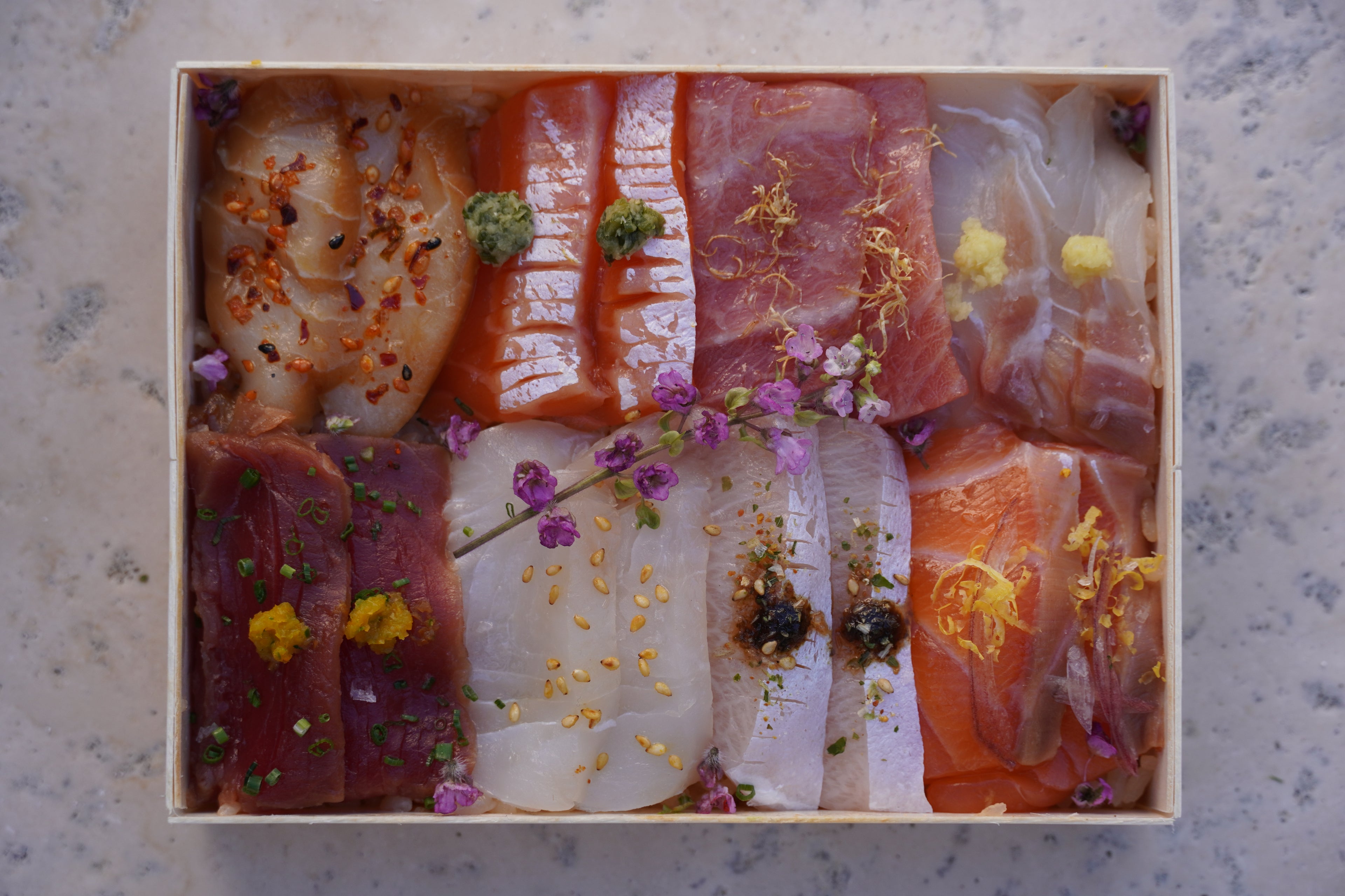 Assorted sushi in a box on a textured surface