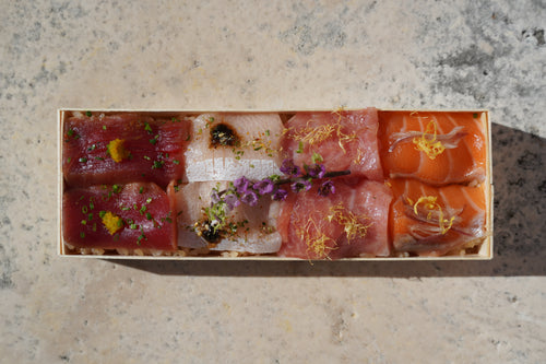 Assorted sushi in a wooden box on a concrete surface 