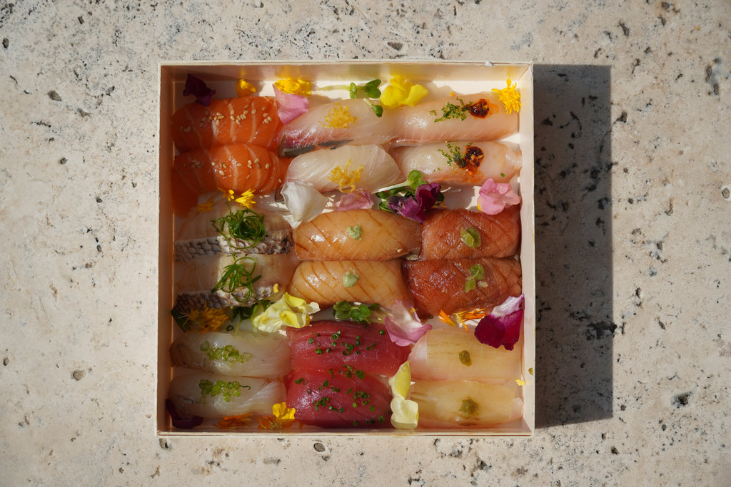 Assorted sushi in a wooden box on a speckled surface