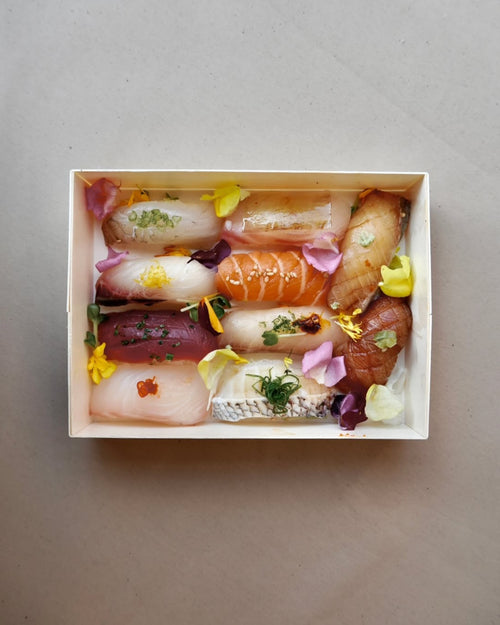 Assorted sushi in a wooden box on a gray background