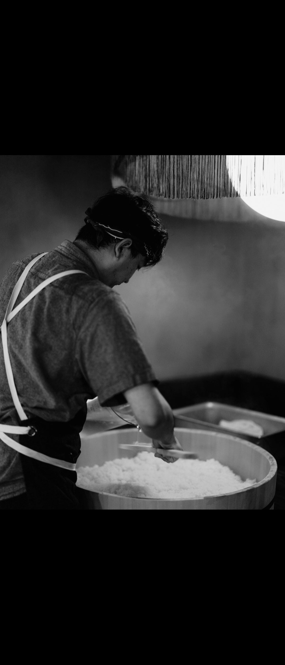 Person making sushi rice with a traditional wooden tub.